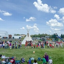 Students participating in a round dance with a tipi