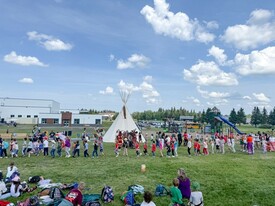 Students participating in a round dance with a tipi