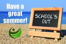 'School's out' written on a blackboard sitting on a beach