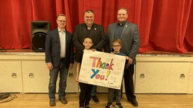 Students presenting community leaders with 'thank you' poster